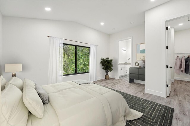 bedroom featuring ensuite bathroom, light wood-type flooring, lofted ceiling, a closet, and a walk in closet