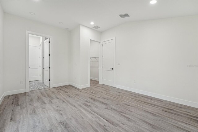 unfurnished bedroom featuring light hardwood / wood-style flooring, a walk in closet, and a closet