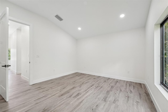 spare room with lofted ceiling and light hardwood / wood-style flooring