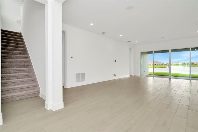 unfurnished living room featuring light wood-type flooring, visible vents, recessed lighting, and stairs