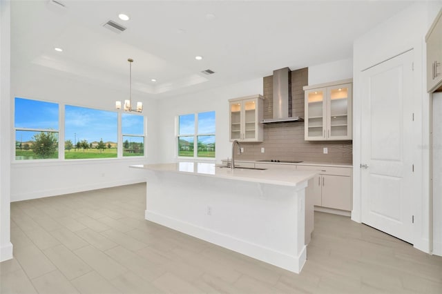 kitchen featuring visible vents, a sink, decorative backsplash, light countertops, and wall chimney exhaust hood