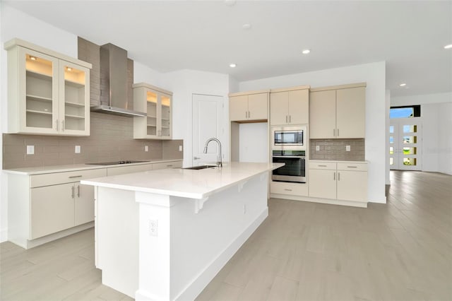 kitchen featuring appliances with stainless steel finishes, light countertops, wall chimney range hood, and a sink