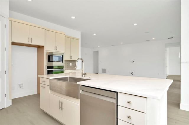 kitchen featuring decorative backsplash, recessed lighting, appliances with stainless steel finishes, cream cabinets, and a sink