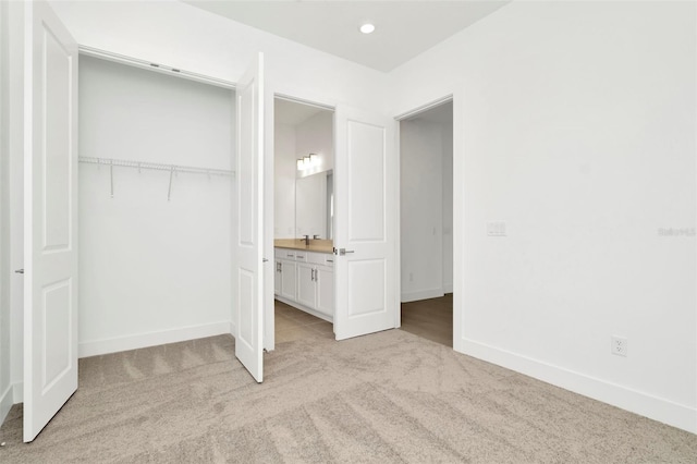 unfurnished bedroom with a closet, recessed lighting, light colored carpet, and baseboards