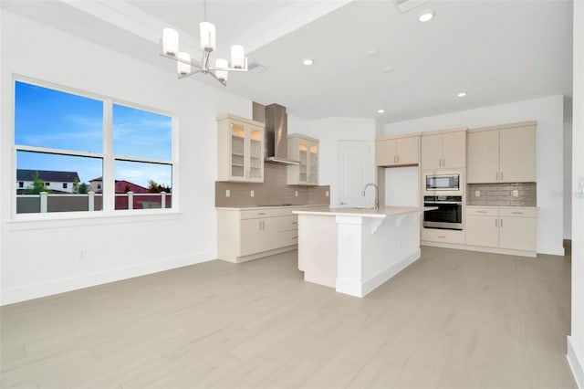 kitchen featuring built in microwave, oven, light countertops, wall chimney range hood, and a notable chandelier