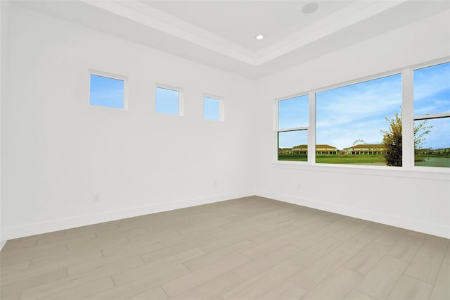 spare room with a tray ceiling, recessed lighting, wood finished floors, and baseboards