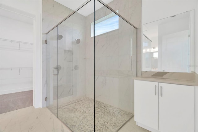 bathroom featuring vanity, a spacious closet, a stall shower, and marble finish floor