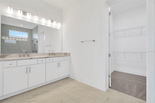 full bath with a sink, tiled shower, marble finish floor, and a spacious closet