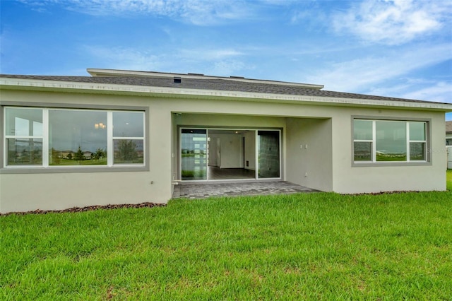 back of house with stucco siding and a yard