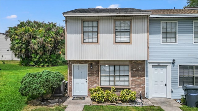 view of front of property with central AC and a front lawn