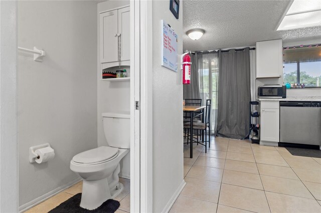 bathroom with a textured ceiling, plenty of natural light, toilet, and tile patterned flooring