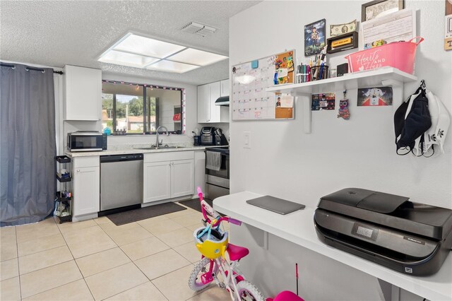 kitchen featuring a textured ceiling, light tile patterned floors, sink, appliances with stainless steel finishes, and white cabinets