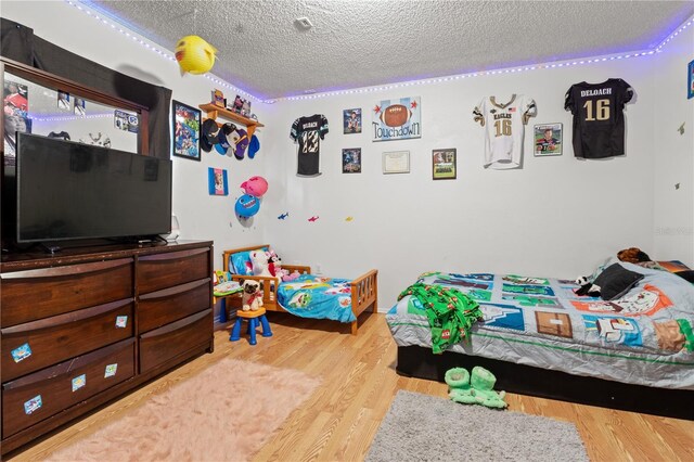 bedroom featuring a textured ceiling and light hardwood / wood-style flooring