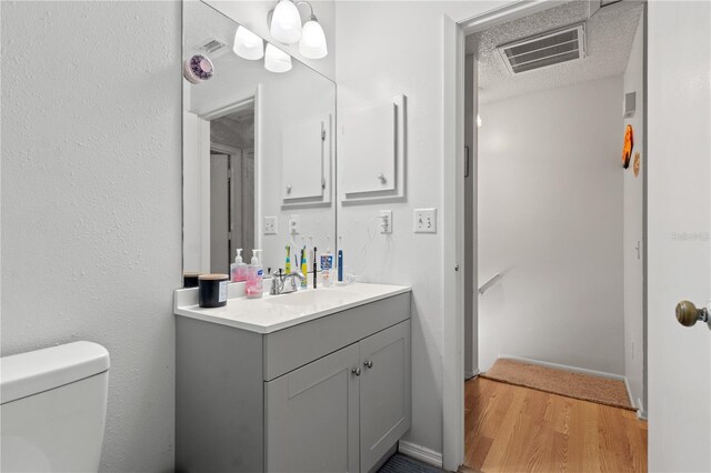 bathroom with vanity, toilet, hardwood / wood-style floors, and a textured ceiling