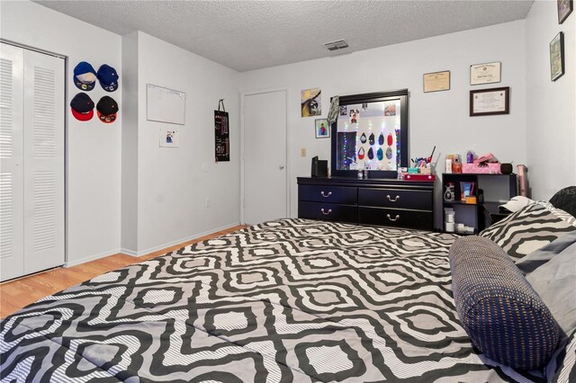 bedroom with a textured ceiling, a closet, and wood-type flooring