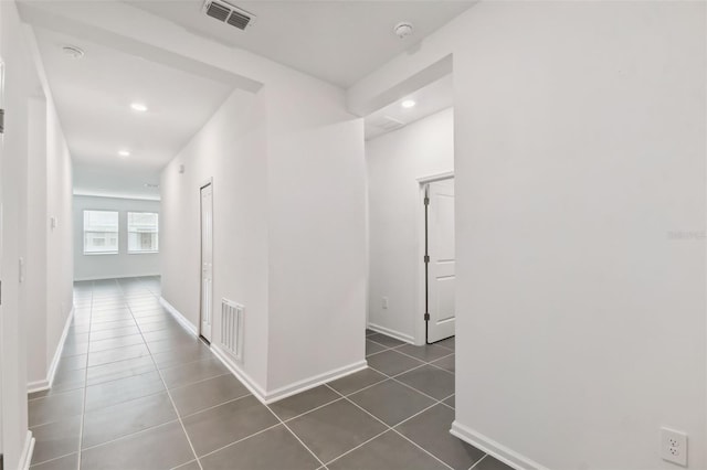 corridor with recessed lighting, dark tile patterned floors, baseboards, and visible vents