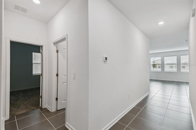 corridor with baseboards, visible vents, recessed lighting, dark tile patterned floors, and dark colored carpet