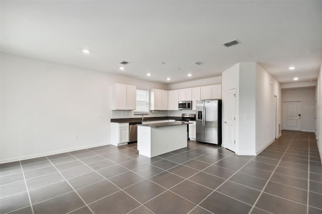 kitchen with dark countertops, visible vents, stainless steel appliances, and dark tile patterned floors