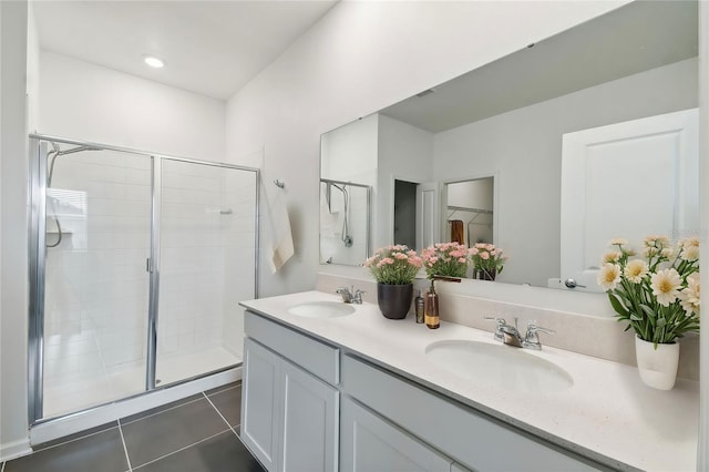 bathroom with tile patterned flooring, a stall shower, double vanity, and a sink