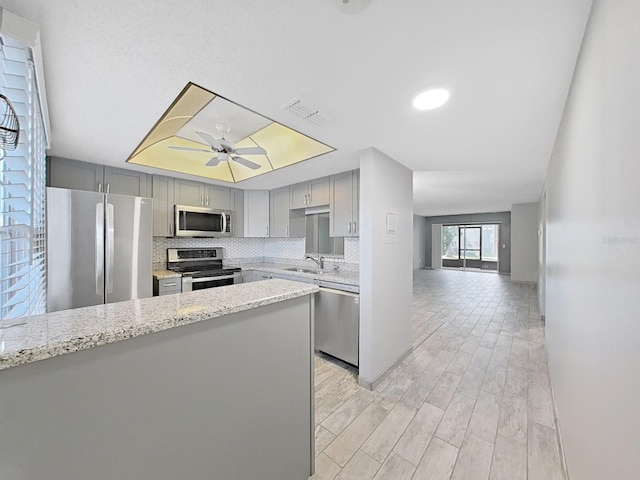 kitchen with light wood-type flooring, stainless steel appliances, sink, ceiling fan, and gray cabinetry