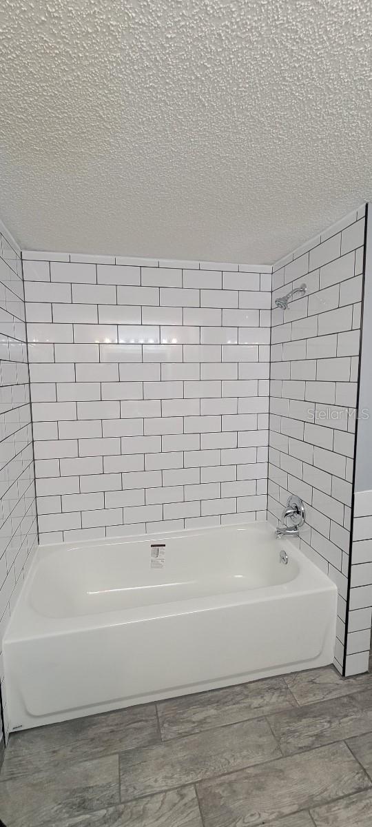 bathroom featuring a textured ceiling, tiled shower / bath combo, and hardwood / wood-style flooring