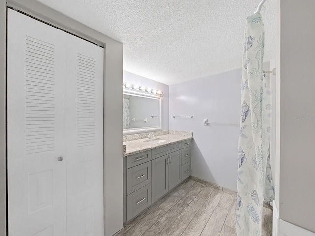 bathroom with a shower with curtain, hardwood / wood-style flooring, a textured ceiling, and vanity