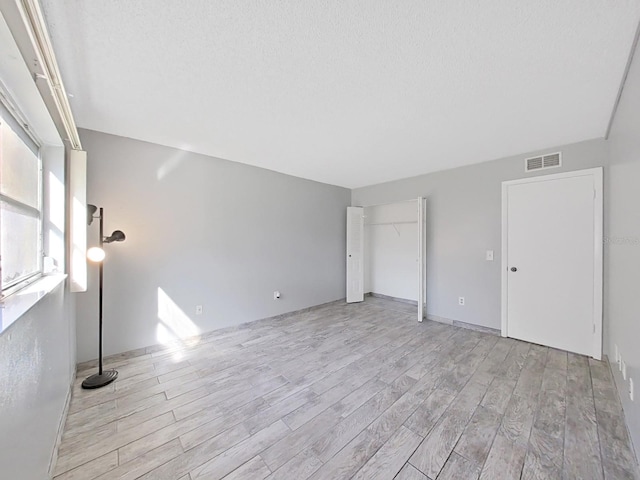 unfurnished bedroom with a textured ceiling and light hardwood / wood-style floors