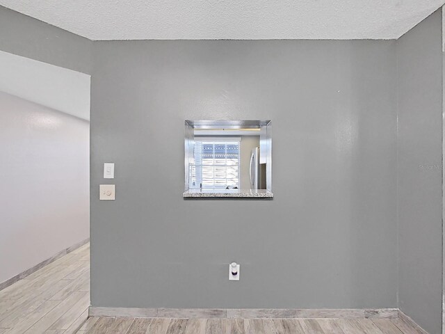 empty room featuring a textured ceiling and light hardwood / wood-style floors