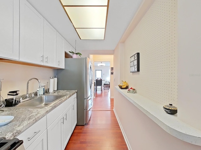 kitchen featuring white cabinets, wood-type flooring, and sink