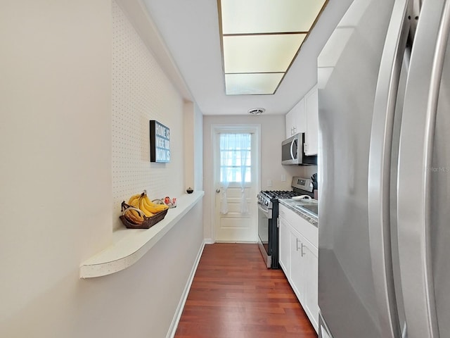 kitchen featuring dark wood-type flooring, appliances with stainless steel finishes, and white cabinetry