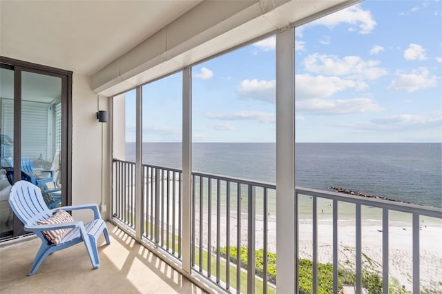 sunroom featuring a beach view, a water view, and a wealth of natural light