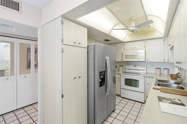 kitchen featuring white appliances, backsplash, sink, ceiling fan, and white cabinets