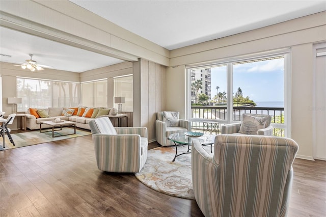 living room featuring hardwood / wood-style flooring, a water view, and ceiling fan