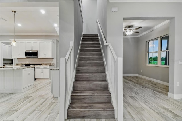 stairway with crown molding, hardwood / wood-style floors, and ceiling fan