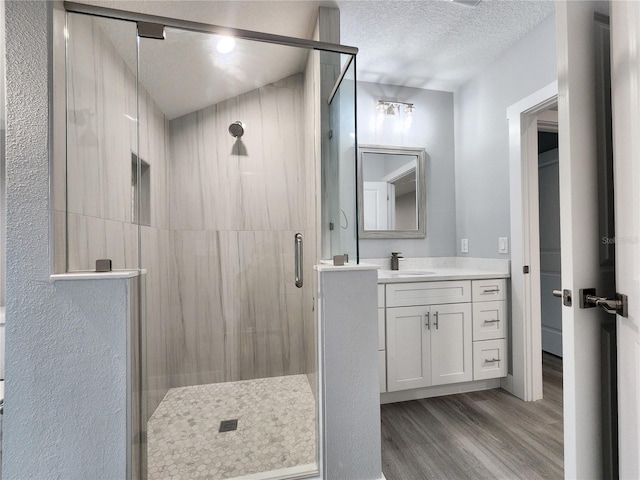 bathroom with vanity, a textured ceiling, a shower with door, and hardwood / wood-style flooring