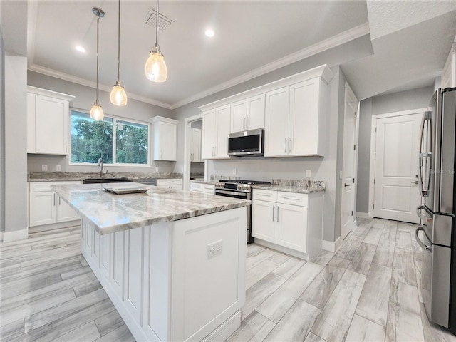 kitchen featuring appliances with stainless steel finishes, hanging light fixtures, light stone counters, white cabinets, and a kitchen island