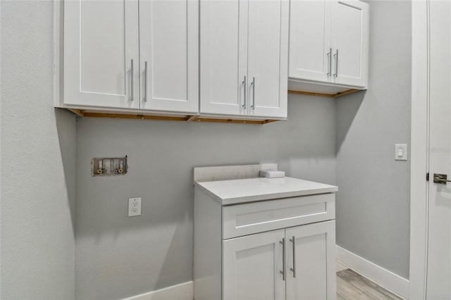 laundry area with cabinets, light hardwood / wood-style flooring, and hookup for a washing machine