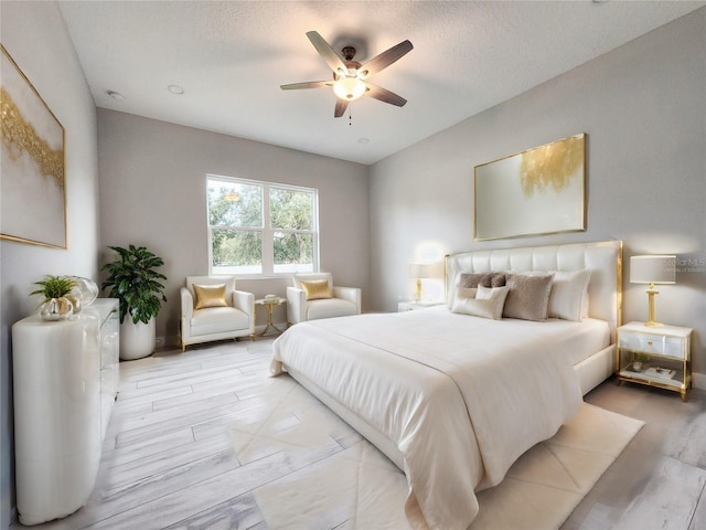 bedroom with ceiling fan, a textured ceiling, and light hardwood / wood-style floors