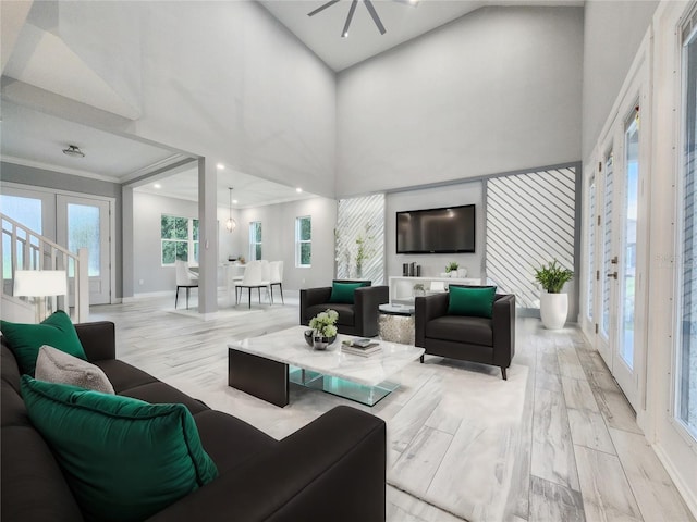 living room with light wood-type flooring, a high ceiling, french doors, and crown molding