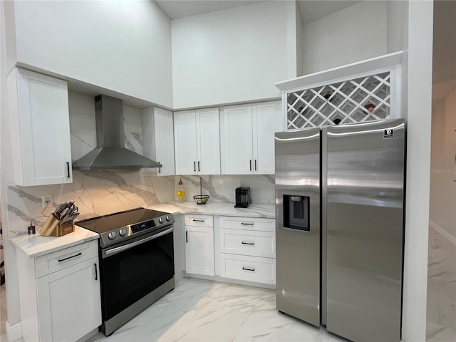 kitchen with wall chimney exhaust hood, tasteful backsplash, stainless steel appliances, and white cabinets