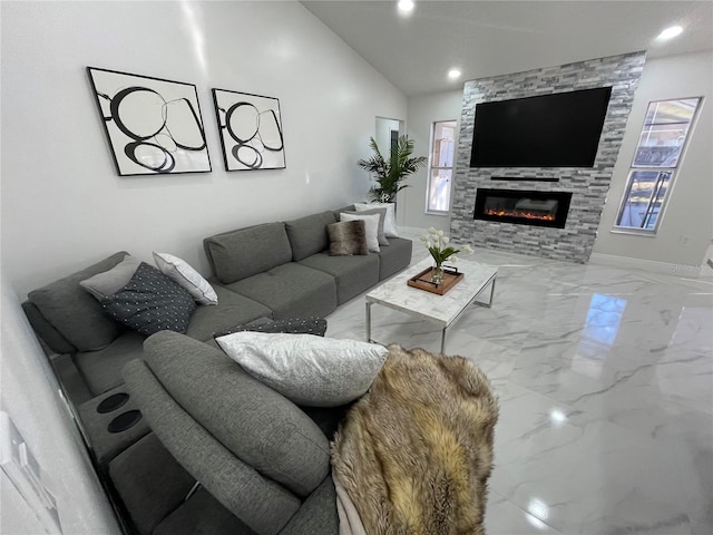 living room with a healthy amount of sunlight, vaulted ceiling, and a stone fireplace