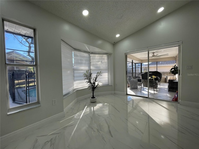 empty room with lofted ceiling, ceiling fan, and a textured ceiling