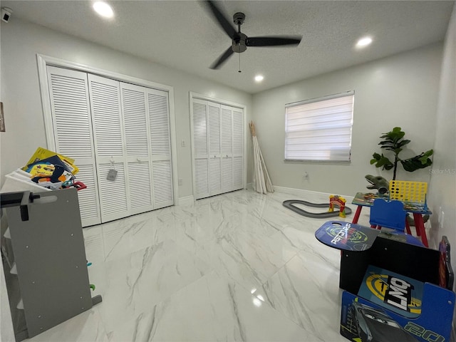 recreation room with a textured ceiling and ceiling fan