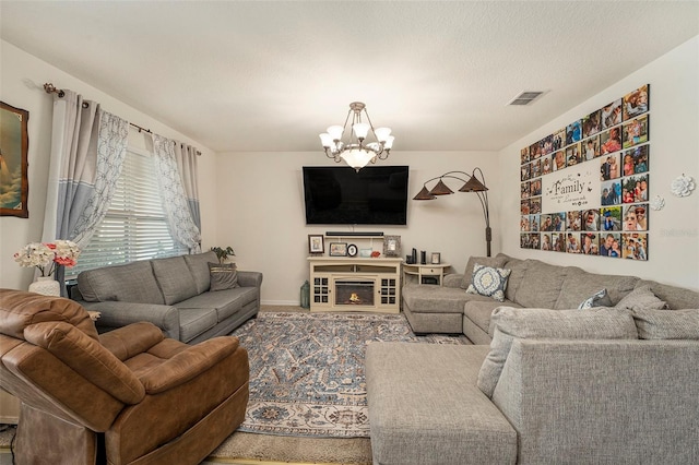 living room with a textured ceiling, a notable chandelier, and carpet flooring