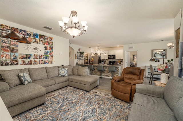 living room with a textured ceiling, an inviting chandelier, and light tile patterned floors