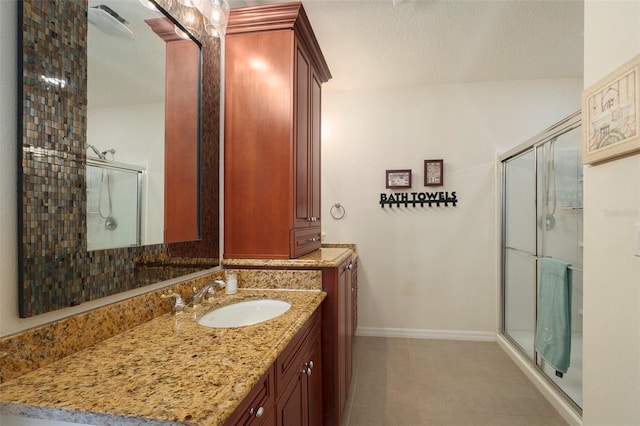 bathroom featuring vanity, a textured ceiling, and a shower with shower door