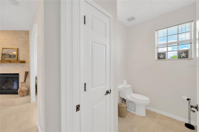 6419 Marbella Blvd, Apollo Beach, FL 33572 - bathroom with toilet, tile patterned flooring, baseboards, and a glass covered fireplace