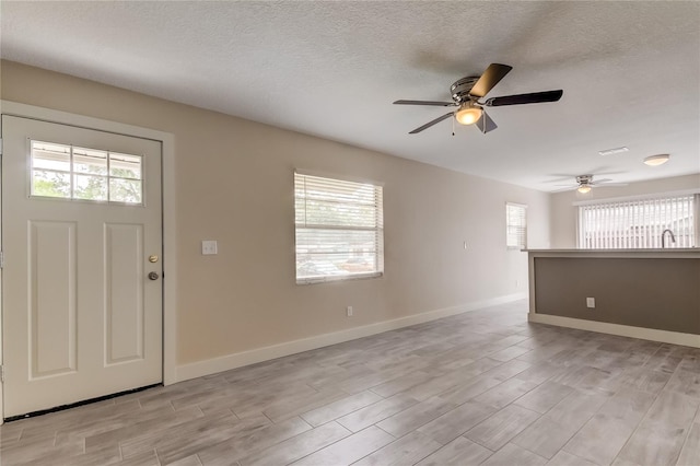 foyer entrance featuring light wood-type flooring, ceiling fan, and a textured ceiling