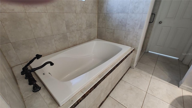 bathroom featuring tile patterned flooring and a relaxing tiled tub