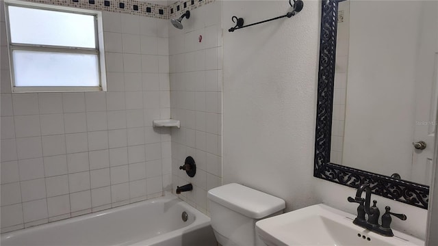 full bathroom with sink, tiled shower / bath combo, and toilet